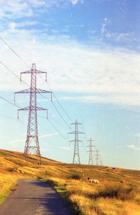 Electricity pylon on road against sky