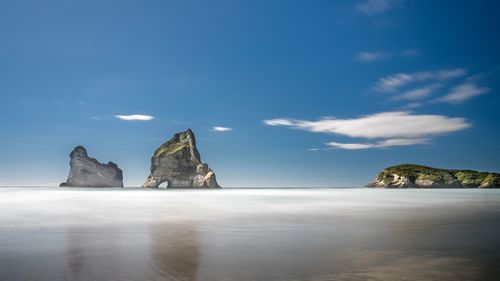 Rock formations on beach against sky