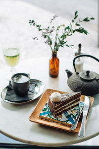 Slice of chocolate cake, teapot, cup of tea on table in outdoors cafe