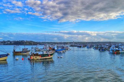 Fishing boats in sea at harbor against sky