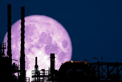 Low angle view of silhouette factory against sky at night