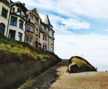 Footpath amidst buildings against sky