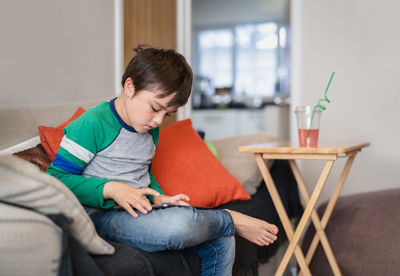 Full length of boy sitting at home