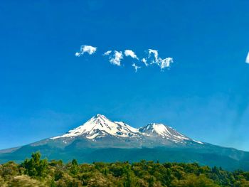 Scenic view of snowcapped mountains against blue sky