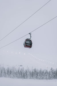 Low angle view of overhead cable car against sky during winter