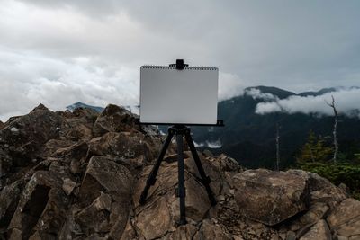 Low angle view of blank placard on rock against sky