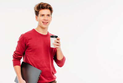 Portrait of smiling young man standing against white background