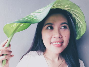 Close-up of smiling woman holding leaf on hair