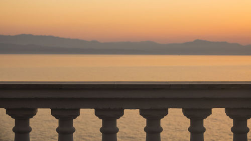 View railing by sea against sky during sunset