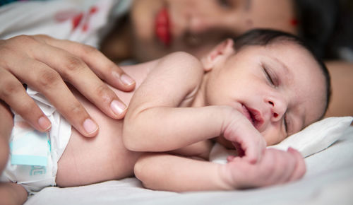 Close-up of cute baby girl lying on bed at home