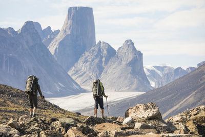 Rear view of people looking at mountains against sky