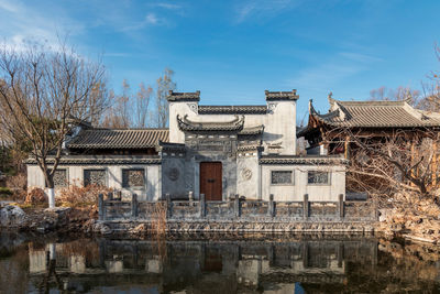 Hui-style architecture by lake against sky