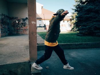 Full length of woman standing against wall in city