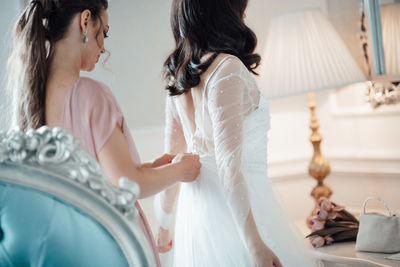 Rear view of bridesmaid grooming bride