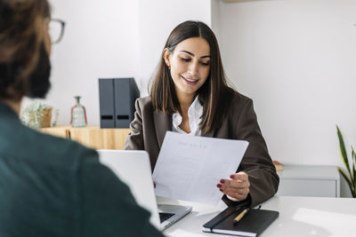 Young recruiter holding candidate resume taking job interview at desk