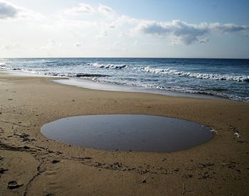 Scenic view of beach against cloudy sky