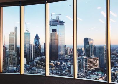 Modern buildings against sky seen through glass window