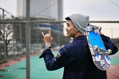 Rear view of young man gesturing outdoors