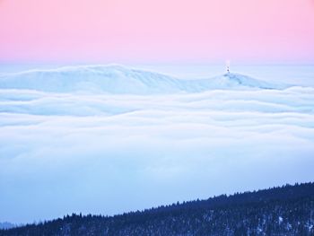 Far mountain peak with observatory above creamy mist. shinning lights on antenna. wavy fog in vallye