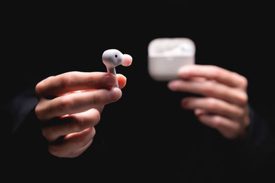 Close-up of hand holding remote control against black background