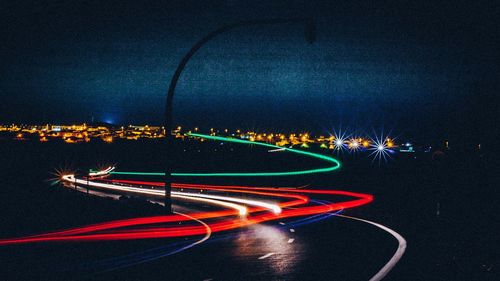 Light trails on road against sky at night