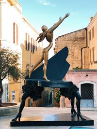 Statue against historic building in city against sky