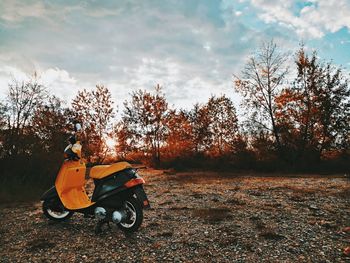 Man riding motorcycle on field against sky during autumn