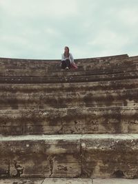 Low angle view of woman sitting at amphitheater against sky