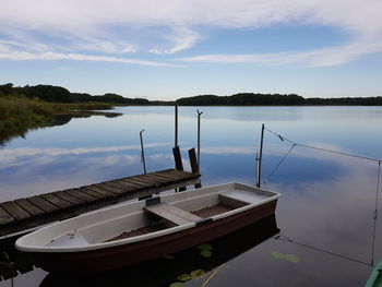 Boat moored in lake against sky