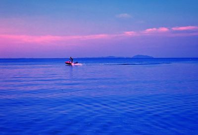 Person jet boating on sea against sky during sunset