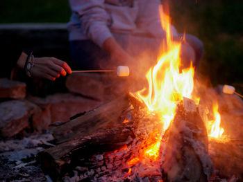 Cropped image of people holding marshmallows at bonfire