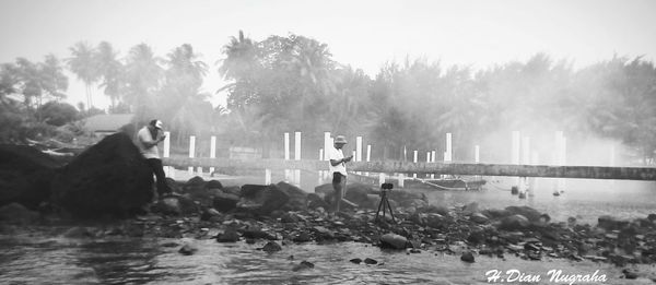 People swimming in river by trees