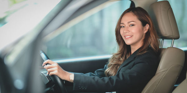 Portrait of a smiling young woman sitting in car