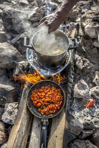 Cropped hand preparing food on wood burning stove