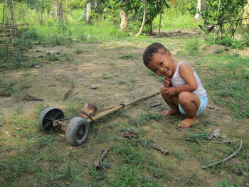Side view of boy sitting on field