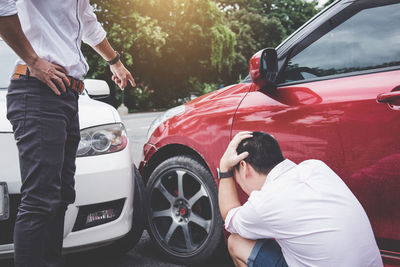 Men standing by car on road