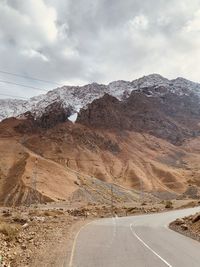 Road by mountains against sky