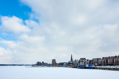 City at waterfront against cloudy sky