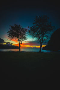 Silhouette trees on landscape against sky at sunset