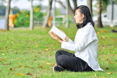 Side view of a young woman sitting on field