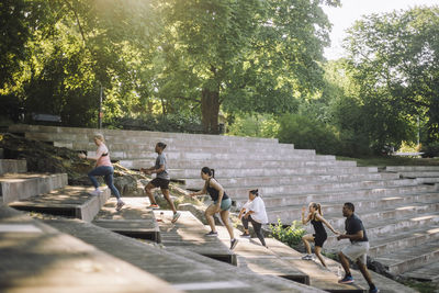 Multiracial team of male and female friends doing warm up on steps