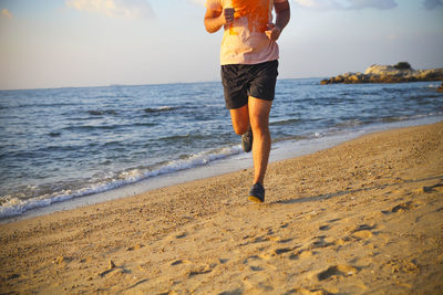 Low section of man running on beach