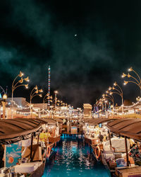 Boats moored at harbor against sky at night