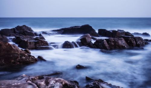 Scenic view of rocks in sea against clear sky