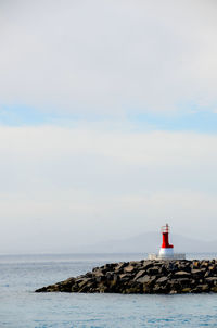 Lighthouse by sea against sky