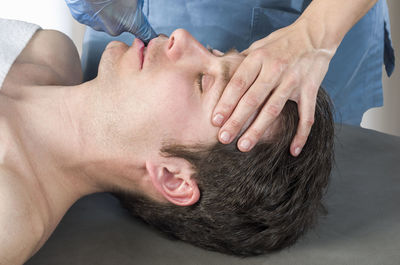 Cropped image of masseur massaging man in spa