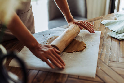 Process of rolling dough for cookies at table, crop on hand