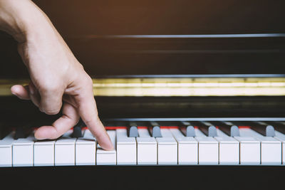 Close-up of hand playing piano