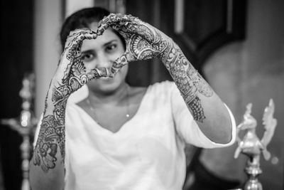 Woman with henna tattoo making heart shape