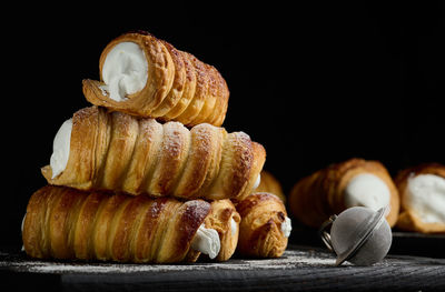 Baked tubules filled with whipped egg whites cream on a black wooden kitchen board